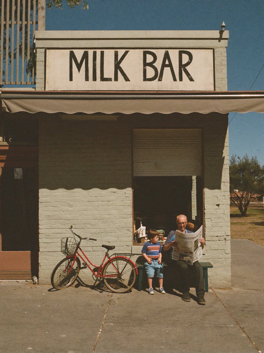 An old corner shop in morning light, a local reading the paper out front.
